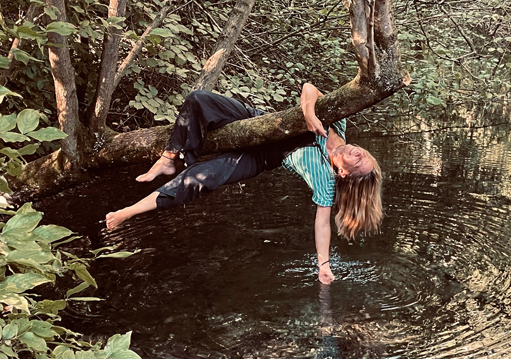 Frau auf Baum am Wasser