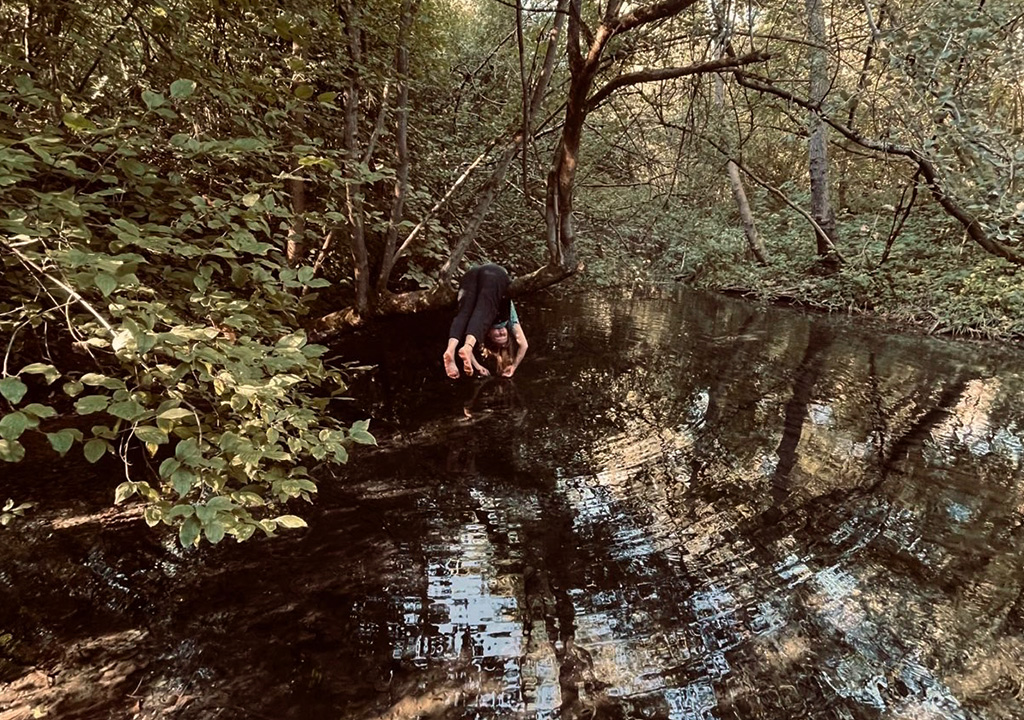 Frau auf Baum am Wasser